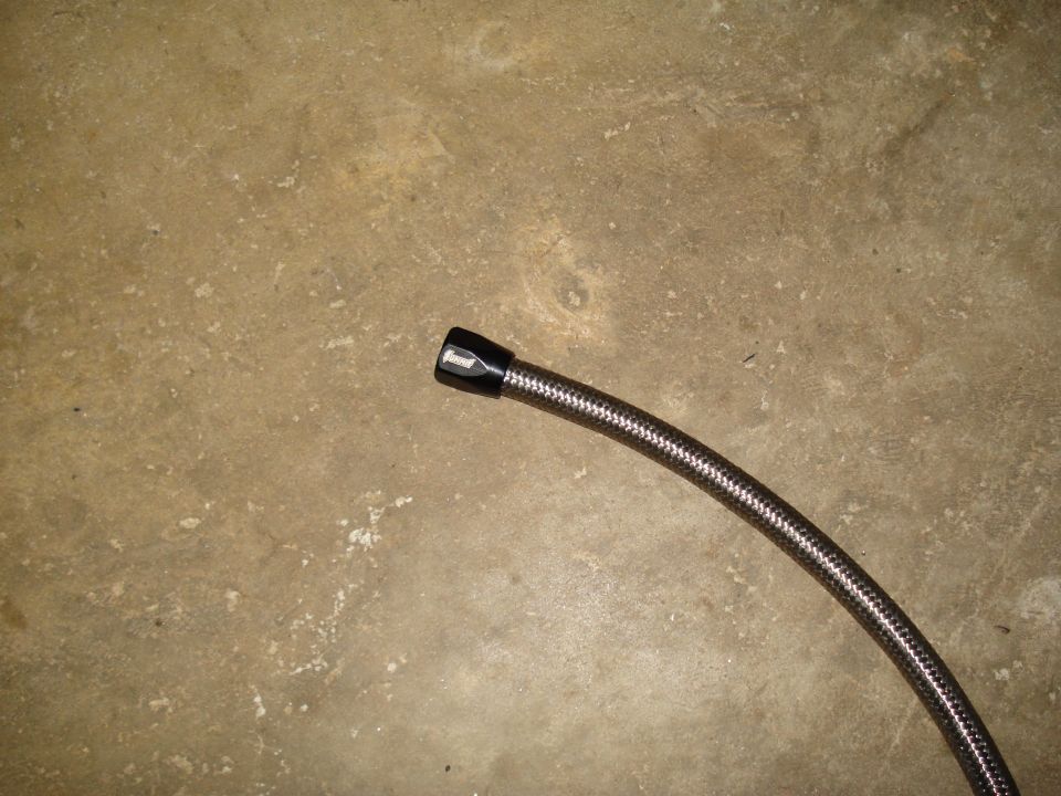 Braided fuel line with black fitting on concrete floor