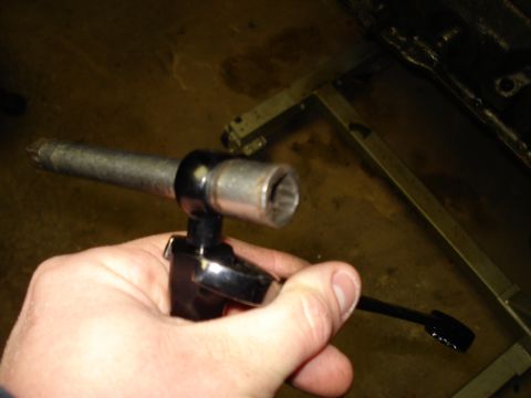 1967 Ford F-250 - A hand holds a socket wrench with an extension and socket, ready for use on a mechanical part.