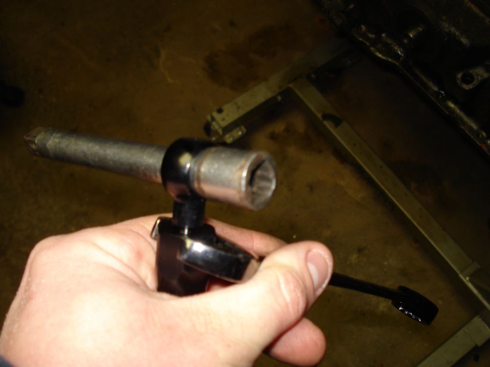 Hand holding a socket wrench with an extension bar and a socket attached