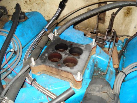 1967 Ford F-250 - Close-up view of an engine's carburetor intake manifold, showing its four ports and surrounding mechanical components.