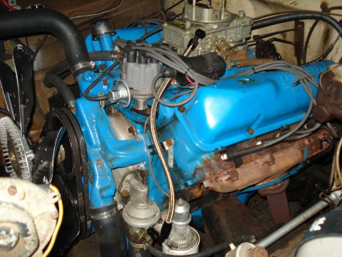 1967 Ford F-250 - Close-up view of a blue engine, showing the carburetor, distributor, and various hoses and belts.