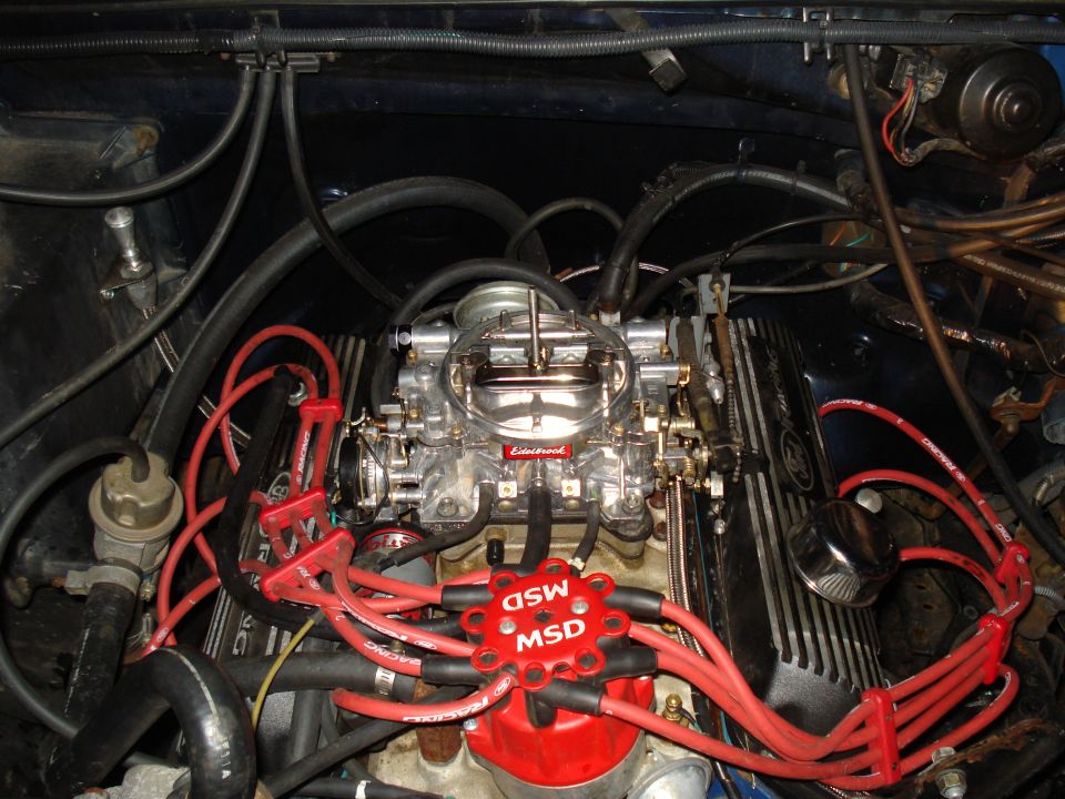 Close-up of an engine bay showing a carburetor and red MSD spark plug wires