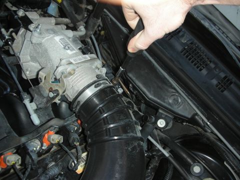 2004 Ford Crown Victoria - Close-up view of engine components, including a throttle body and intake hose, during a repair or modification.