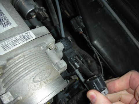 2004 Ford Crown Victoria - Close-up of a Ford throttle body and electrical connector being disconnected.