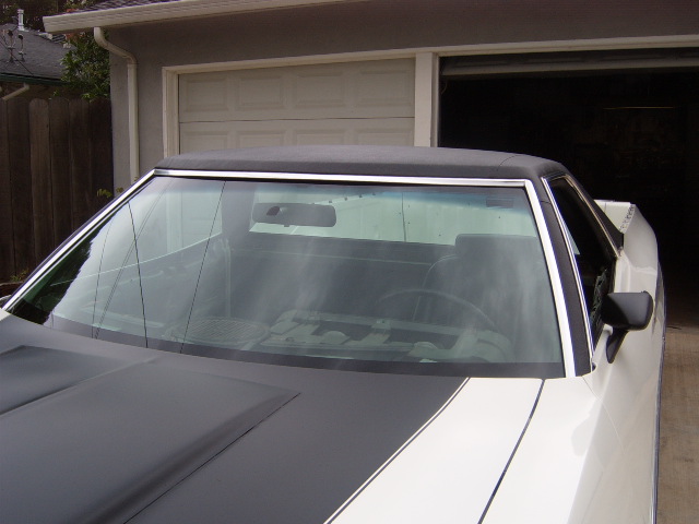 White 1972 Ford Ranchero with black hood stripes, parked in front of a garage
