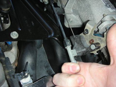 2004 Ford Crown Victoria - Close-up of a hand manipulating the throttle body linkage and cable assembly.
