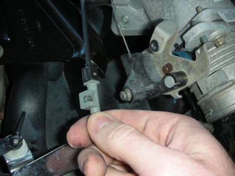 2004 Ford Crown Victoria - Close-up of a hand manipulating a throttle cable connection on a vehicle's throttle body.