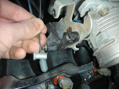 2004 Ford Crown Victoria - Close-up of a hand manipulating a throttle cable during an engine part installation.
