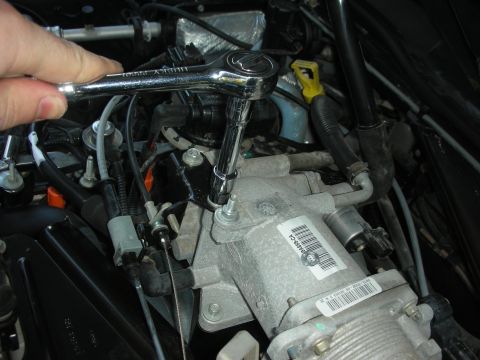 2004 Ford Crown Victoria - Mechanic's hand using a socket wrench to work on a vehicle's engine intake manifold.