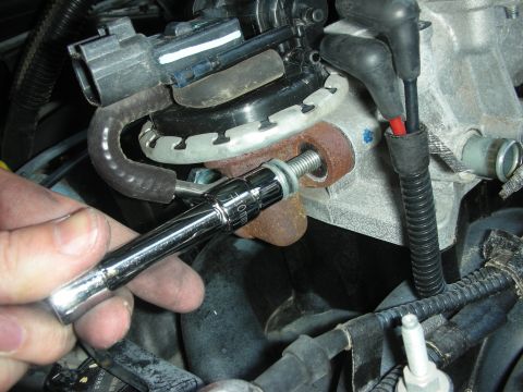 2004 Ford Crown Victoria - Close-up of a hand working on an engine component with a socket wrench.