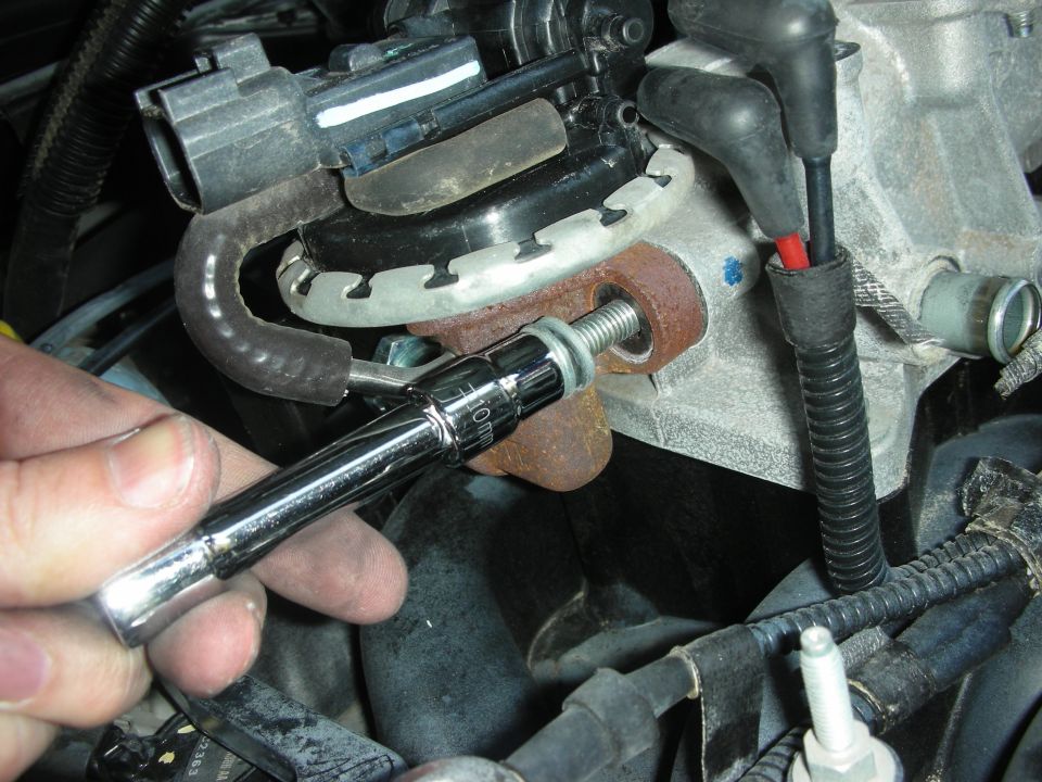 hand using 10mm socket wrench on bolt of engine part