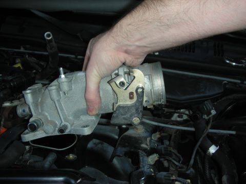 2004 Ford Crown Victoria - A hand holds a Ford throttle body and intake manifold assembly during an engine repair.