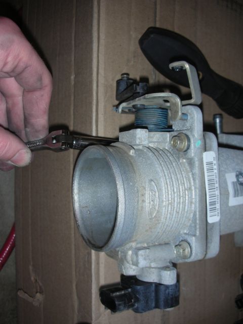 2004 Ford Crown Victoria - A hand uses a wrench on a Ford throttle body, likely for installation or maintenance.