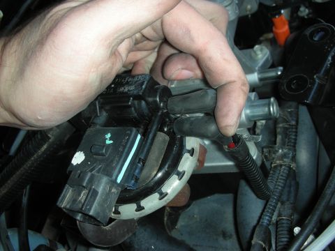 2004 Ford Crown Victoria - Close-up of a hand disconnecting an electrical connector from an engine part.