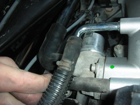 2004 Ford Crown Victoria - Close-up view of engine components, including intake manifold and throttle body, with a hand visible.