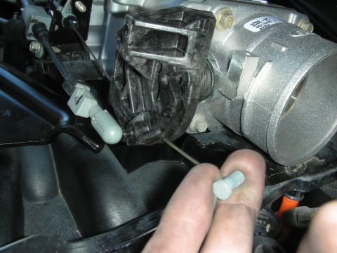 2004 Ford Crown Victoria - Close-up view of a vehicle's throttle body and intake manifold assembly, with a hand holding a small bolt.
