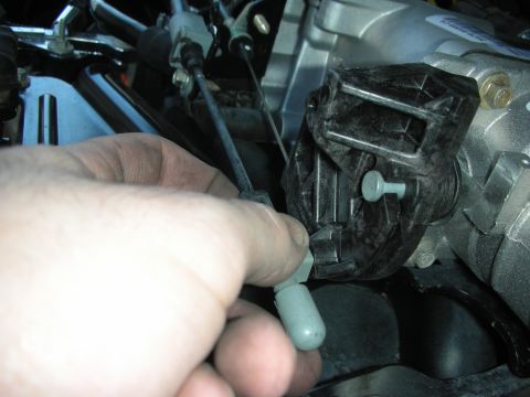 2004 Ford Crown Victoria - Close-up of a hand manipulating a throttle cable connected to a black plastic component on an engine.