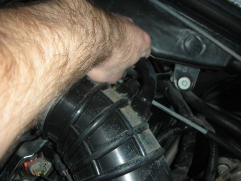 2004 Ford Crown Victoria - Close-up of a hand connecting a hose to an engine intake part.
