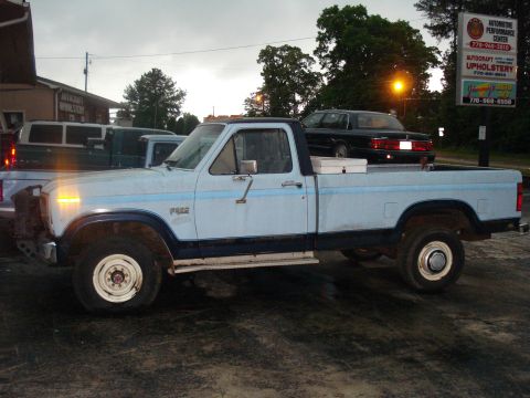 1967 Ford F-250 - A light blue pickup truck is parked next to other vehicles outside an automotive center.
