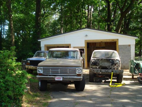 1967 Ford F-250 - Three pickup trucks are parked outside a garage. The middle truck has a license plate that reads 'BEEF'.