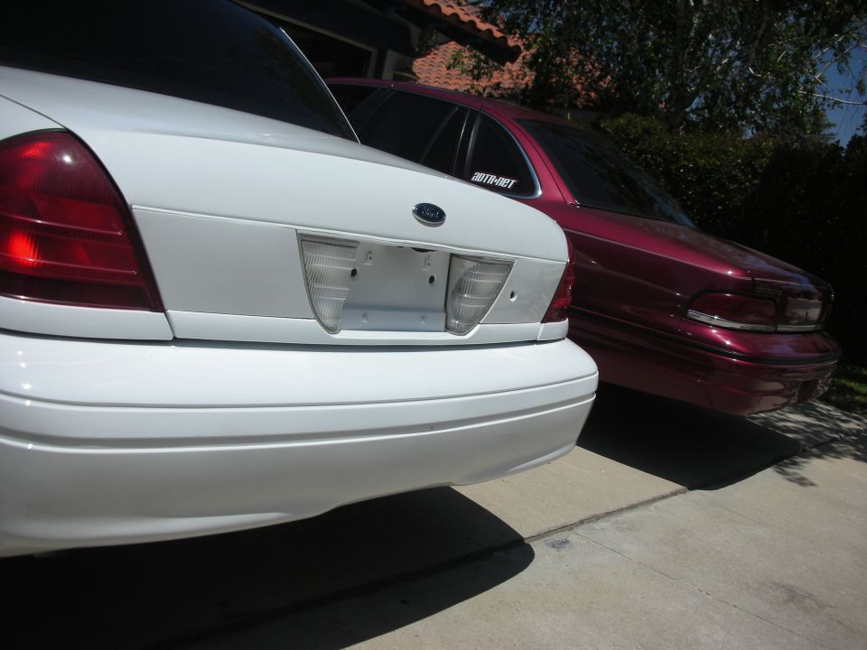 Rear view of white 2004 Ford Crown Victoria parked next to a maroon Ford Crown Victoria