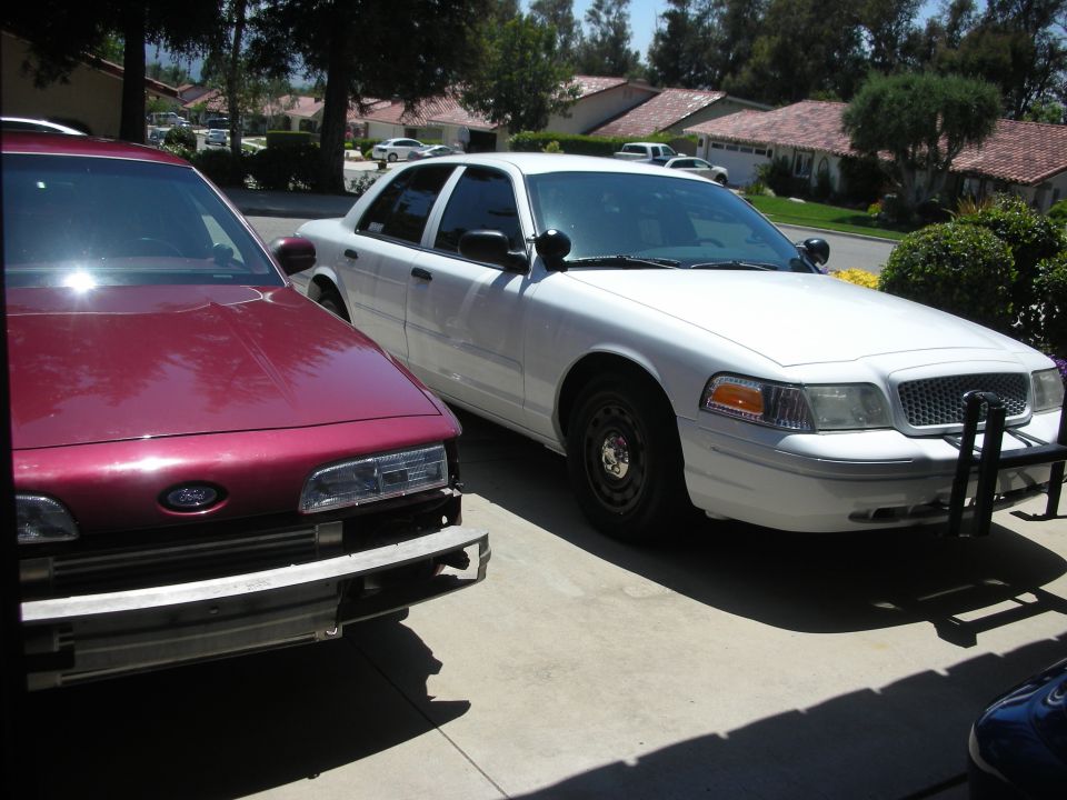 White police car with push bumper parked next to a maroon car missing its front bumper