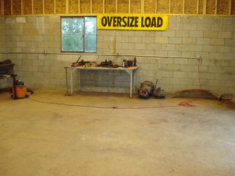 1967 Ford F-250 - Workshop scene with automotive parts including two transmissions and a leaf spring, under an 'Oversize Load' banner.