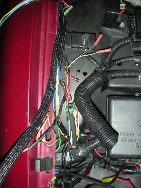 1992 Ford Crown Victoria - Close-up of a complex wiring harness and fuse box, possibly from an intercooler project, on a red vehicle fender.
