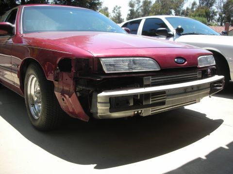 1992 Ford Crown Victoria - Front view of a red 1992 Ford Crown Victoria undergoing modifications, with its bumper removed to expose the intercooler. A white vehicle i…