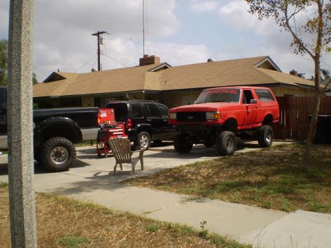 1969 Ford F-250 - Two trucks and an SUV are parked in a driveway with a house in the background.
