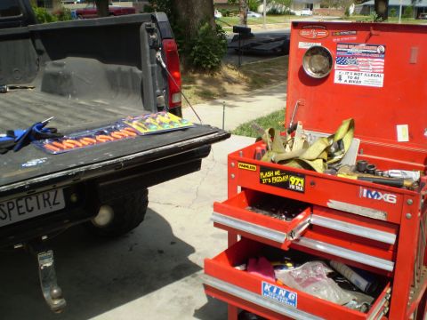 1969 Ford F-250 - A red toolbox sits next to the open tailgate of a black pickup truck, filled with various tools.