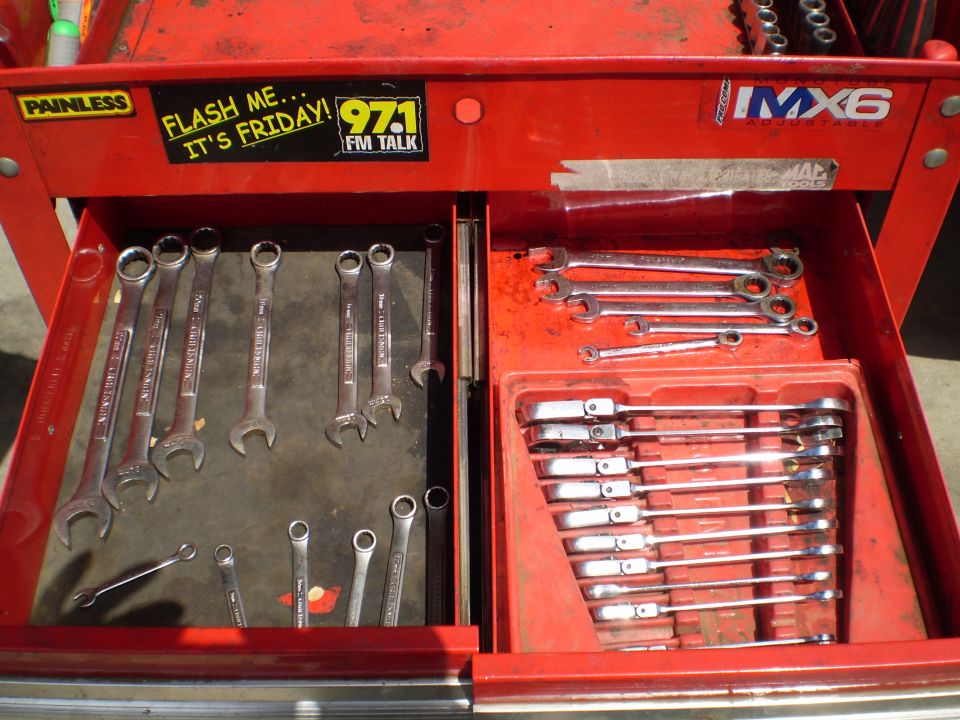 Red tool chest with open drawers filled with wrenches