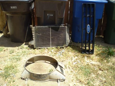 1969 Ford F-250 - A black Ford grille and a radiator are displayed outdoors next to trash cans.