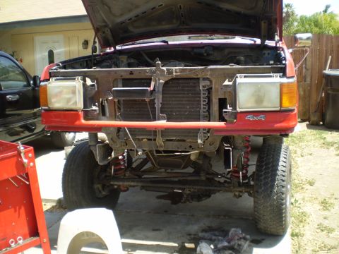 1969 Ford F-250 - Front view of a red pickup truck with its hood open, revealing the engine bay and a 4x4 badge on the bumper.