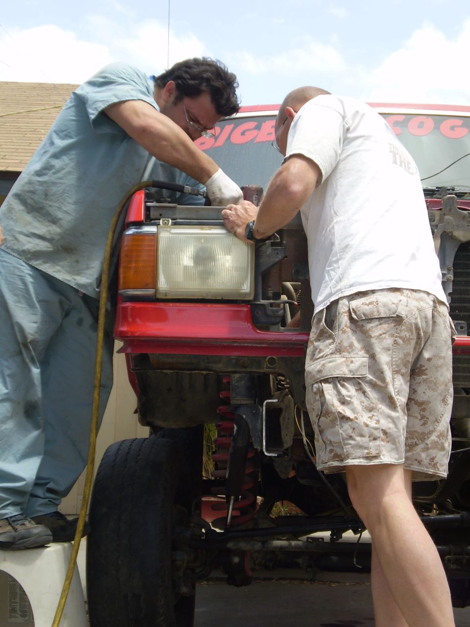 Red truck front end with men working on it. Supermotors.net logo visible