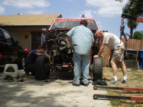 1969 Ford F-250 - Men are working on the engine of a red truck with "BIGBRONCOGIRL" on the windshield.