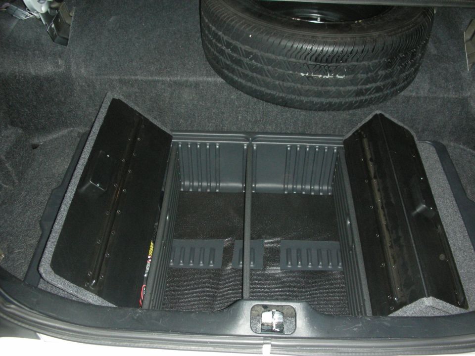 Open sedan trunk with carpet, full-size spare tire and divided black organizer trays