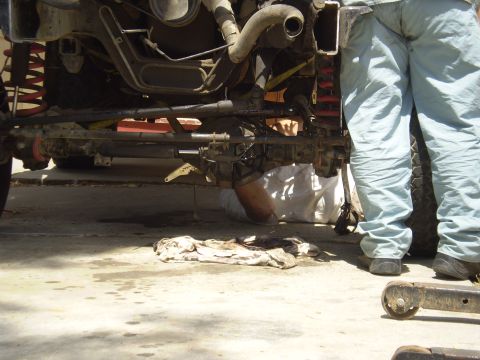 1969 Ford F-250 - Mechanics work on the undercarriage of a vehicle, focusing on the suspension and drivetrain components.
