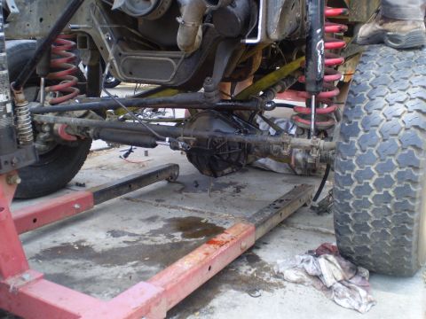 1969 Ford F-250 - The front suspension and drivetrain of a truck are visible while it's supported by a frame machine.