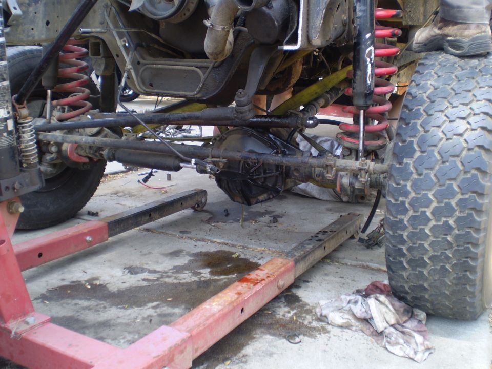 Truck chassis on a red frame machine, showing suspension and drivetrain components