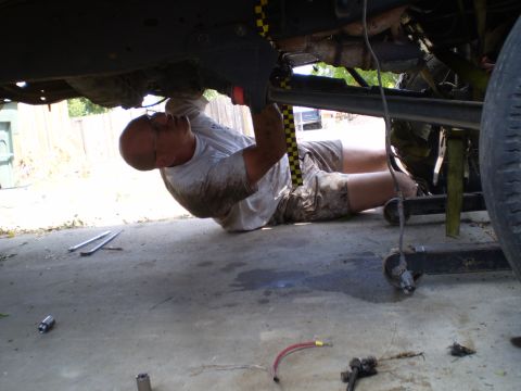 1969 Ford F-250 - A mechanic works on the underside of a vehicle, with the Supermotors.net logo visible in the corner.