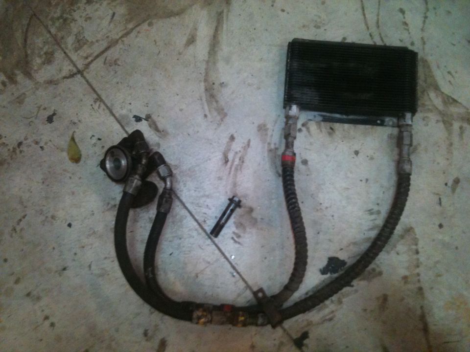 Power steering pump, braided hoses and finned cooler laid out on a garage floor