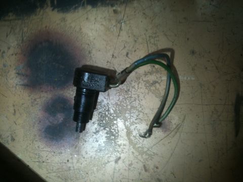 1989 Ford Bronco - A black automotive sensor with attached wires lies on a textured surface.