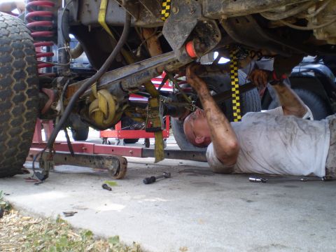 1969 Ford F-250 - Undercarriage work being done on a lifted vehicle with a mechanic underneath.