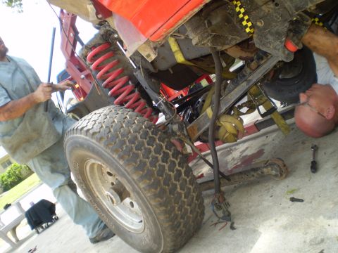 1969 Ford F-250 - Two people are working on the suspension and drivetrain of a vehicle that appears to be modified for off-road use.