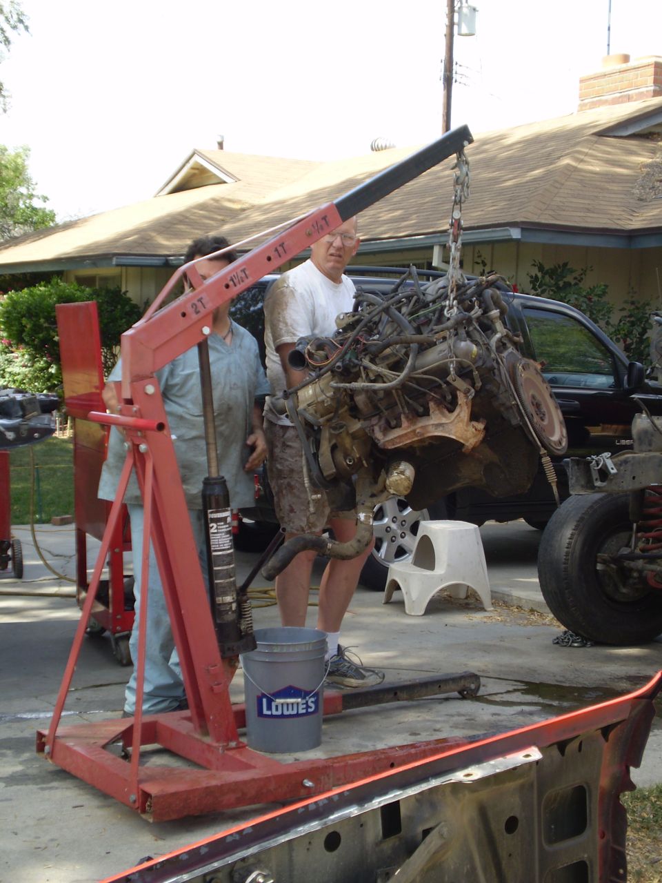 Engine being lifted out of a dark-colored truck with an engine hoist