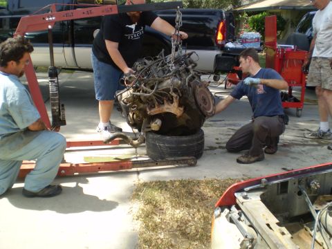 1969 Ford F-250 - Mechanics work together to carefully remove a vehicle's engine using an engine hoist.