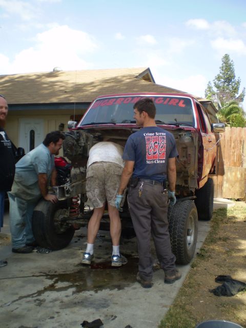 1969 Ford F-250 - Several people work on the engine of a red truck that has had its front end disassembled.