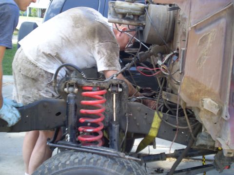 1969 Ford F-250 - Mechanics work on the engine and suspension of a truck, possibly a 1967 model.