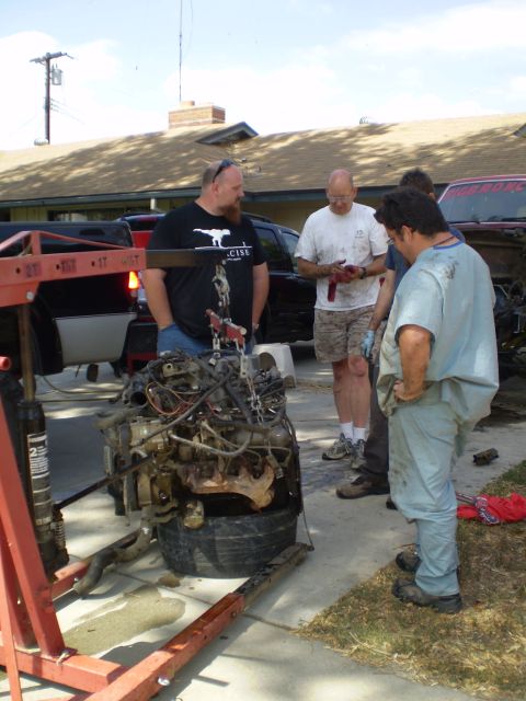 1969 Ford F-250 - Men gathered around an engine being removed or installed with an engine hoist.